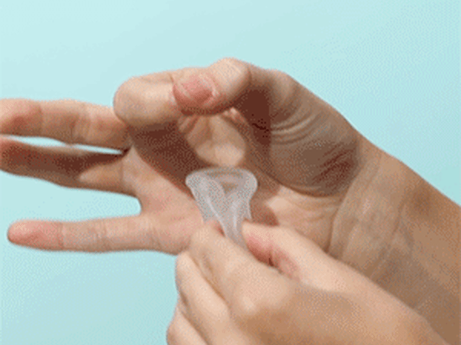 Gif of someone inserting a menstrual cup in between a hold made with thumb and forefinger