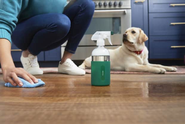 person cleaning wood floors with spray cleaner and cloth