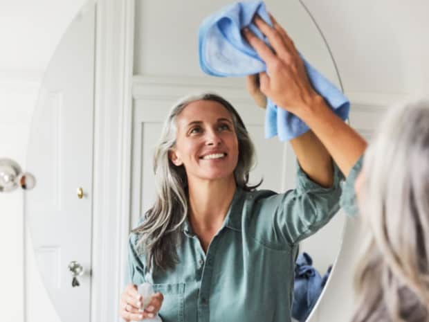 Image of a woman wiping down a mirror