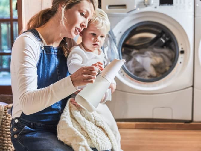 Image of a woman showing a child a container of laundry detergent.