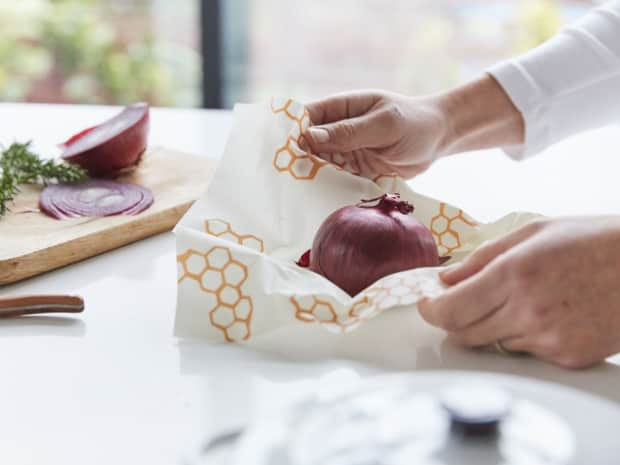 person wrapping onion in bees wrap