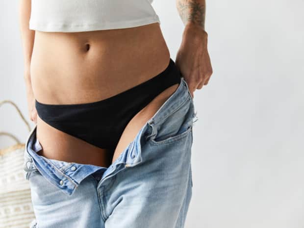 Person wearing period underwear and putting on jeans