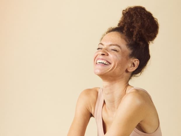 Photo of woman smiling in front of beige background