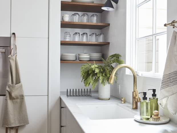 Kitchen cupboards and open shelving next to a sink and kitchen window
