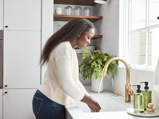 An image of a woman washing her hands in a sink.