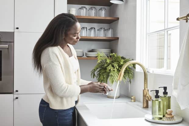 Woman washing hands in kitchen sink