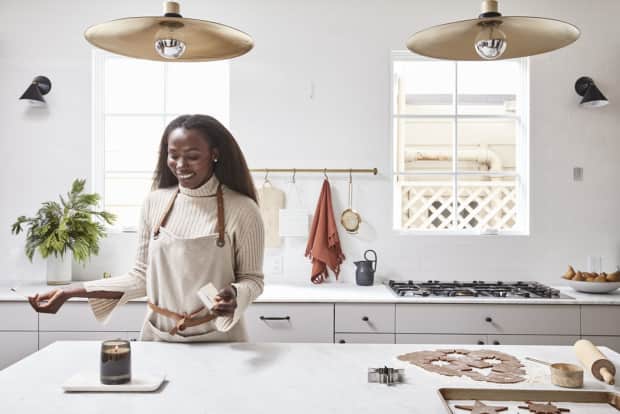 Woman lighting candle on counter in kitchen