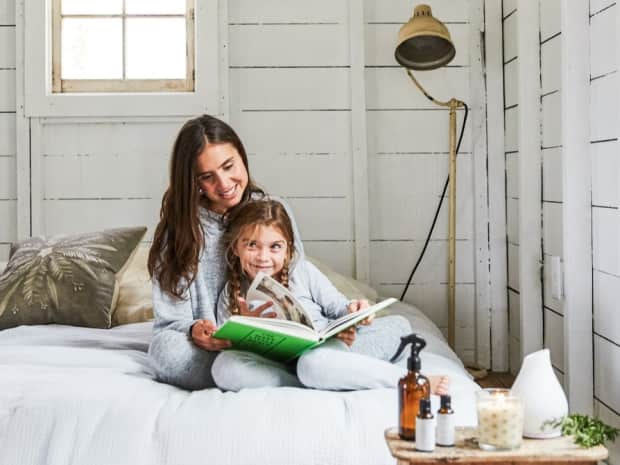 An adult and young child sitting together reading on their clean mattress