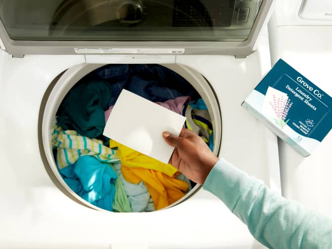 Image of person holding sheet in front of laundry machine opening