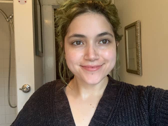 Photo of woman smiling and wearing moisturizer