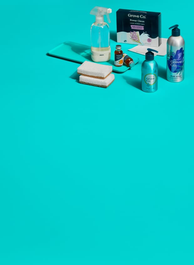 Grove Co. hand and dish soaps, laundry sheets, multi surface cleaner and walnut scrubber sponges sitting on a counter top.