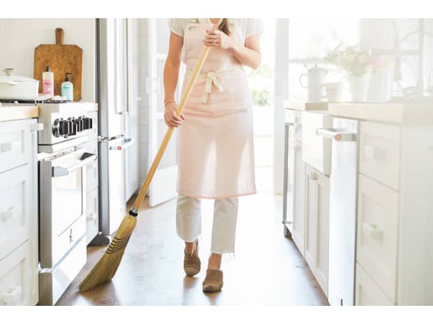 Women sweeping in front of oven