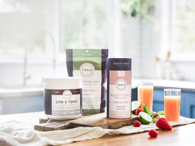 Photo of Tonic products on table with fruits and glasses of juice