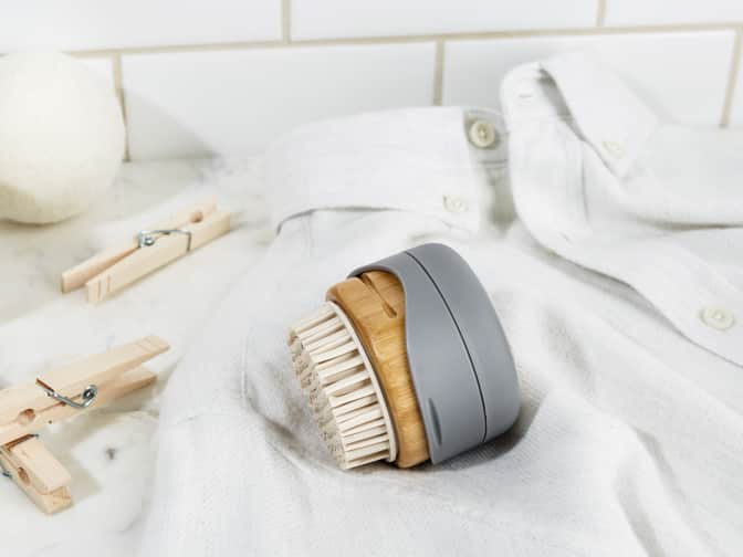 Image of Grove Co. reusable lint brush on its side on top of white sheet