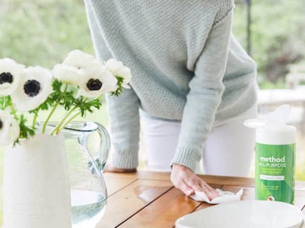 woman spraying down countertops by daisies