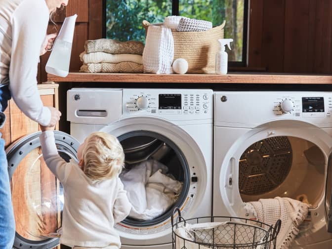 Image of parent and child standing in front of white washing and drying machine