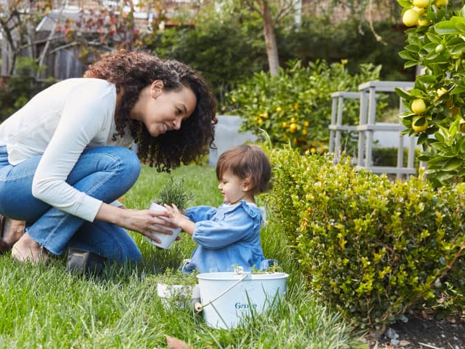 Young mother outside in the garden with her toddler daughter and Grove Collaborative caddy