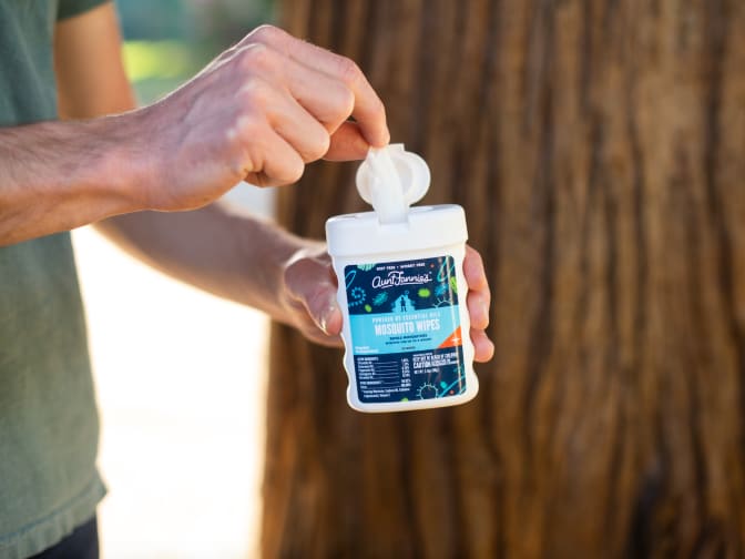 Image of person pulling wipe out of Aunt Fannie's Mosquito Wipe container