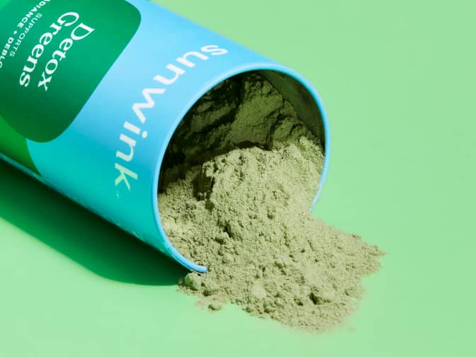 Image shows Sunwink detox greens spilling over onto a green background.