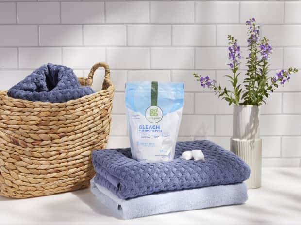 Image of Grab Green Bleach Alternative bag and pods on freshly folded towels next to wicker basket