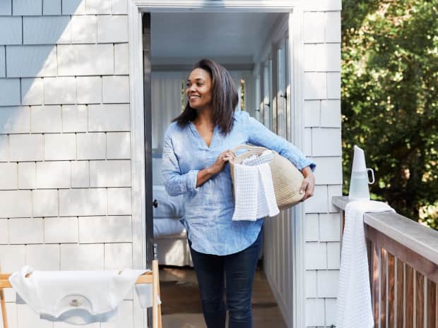 woman bringing laundry basket outside to hang laundry