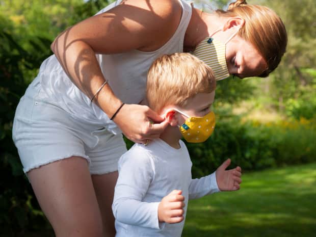 image of parent wearing a cloth face mask and putting cloth face mask on a child