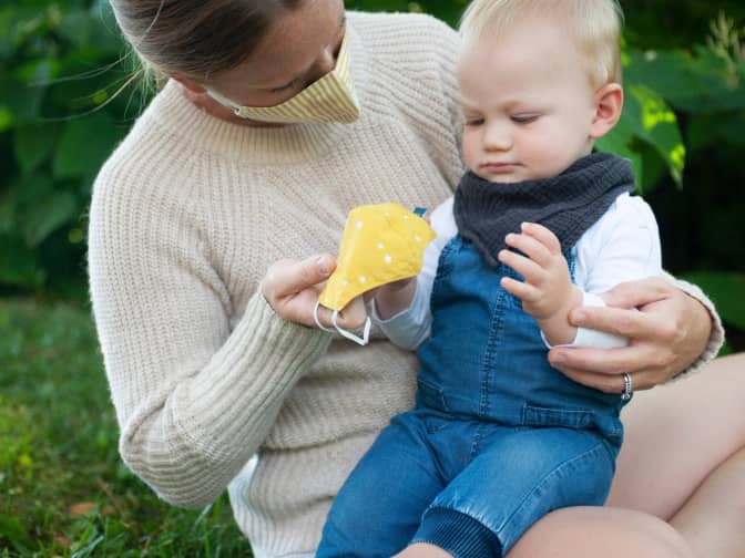 image of parent in cloth mask handing a cloth face mask to small child