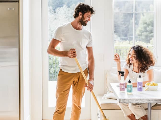 Two people laughing and enjoying cleaning their laminate wood floors with natural cleaners.