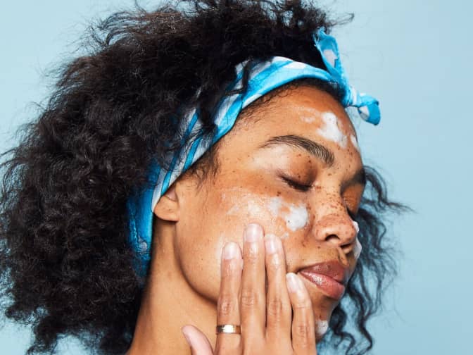 Photo of woman with headband on washing face