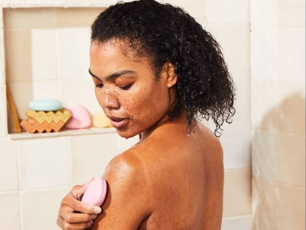 Image of woman in shower using bar soap on arm