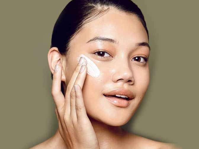 Photo of woman applying cream to cheek