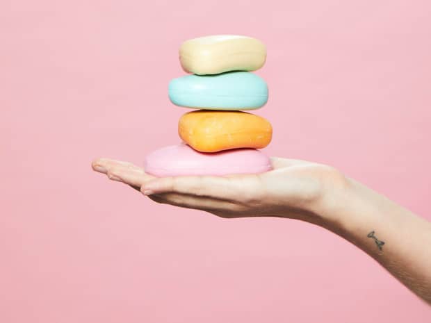 Image of person holding 4 bars of soap stacked in palm of hand