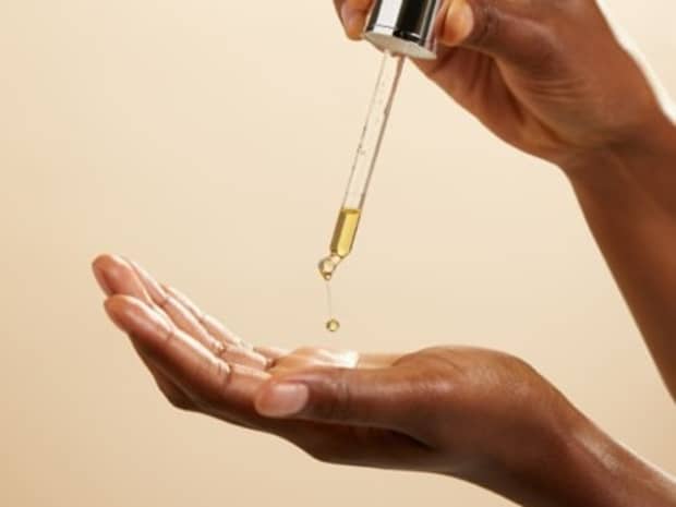 Image of someone's hands pouring oil from a dropper into their palm.