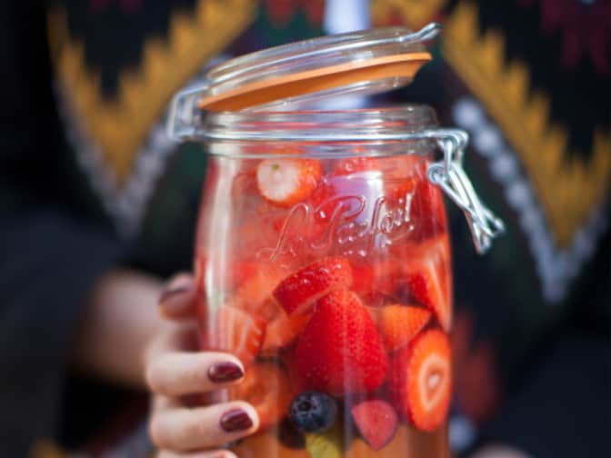 Image of a woman holding Le Parfait Glass Storage with berries and liquid inside.