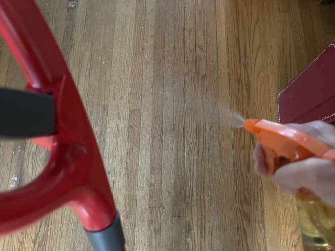Someone spritzing their hardwood floors with cleaner.