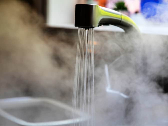 Photo of sink with tap running and air full of steam