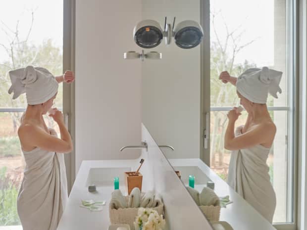 woman putting deodorant on her underarms