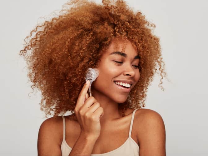 Photo of woman exfoliating face with brush