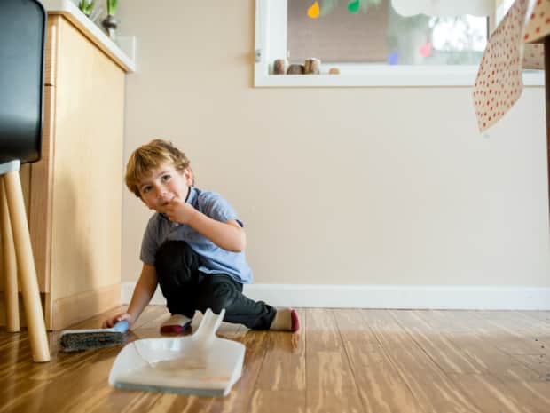 Image of a child sweeping up dirt on bamboo floors.