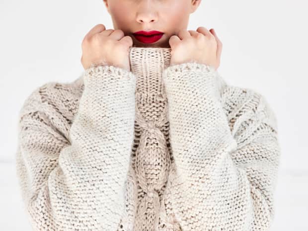 Woman with lipstick covering up with a winter sweater