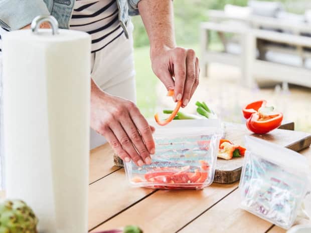 person storing fresh vegetables in sealed bags