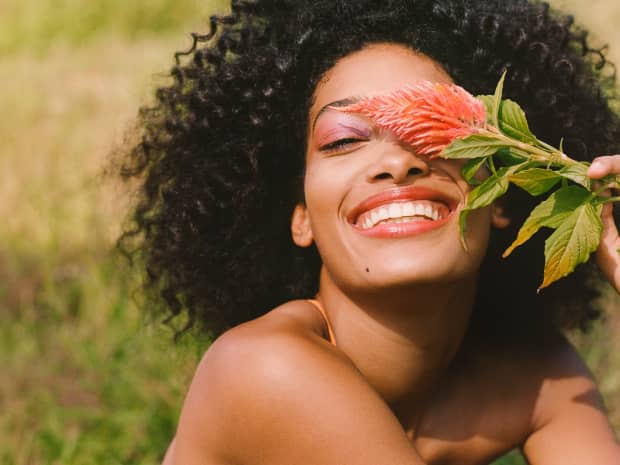 Image of a woman smiling with a flower. 