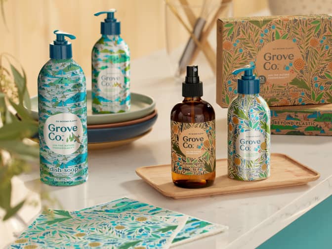 Image shows Grove Co's summer collection on a countertop. Collection includes aluminum dish soap, aluminum hand soap, glass room spray, swedish dish cloths, and laundry detergent sheets.
