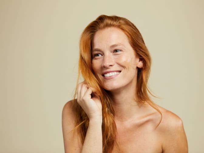 Redhead woman smiling in a beauty headshot