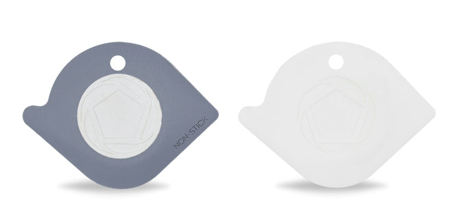 Two recycled plastic, flat Pentagon-shaped Power Couple Pan Scrapers by Full Circle are shown. One is gray with a NON-STICK label, and the other is white. These scrapers have circular centers and a top hole for easy storage without scratching surfaces.