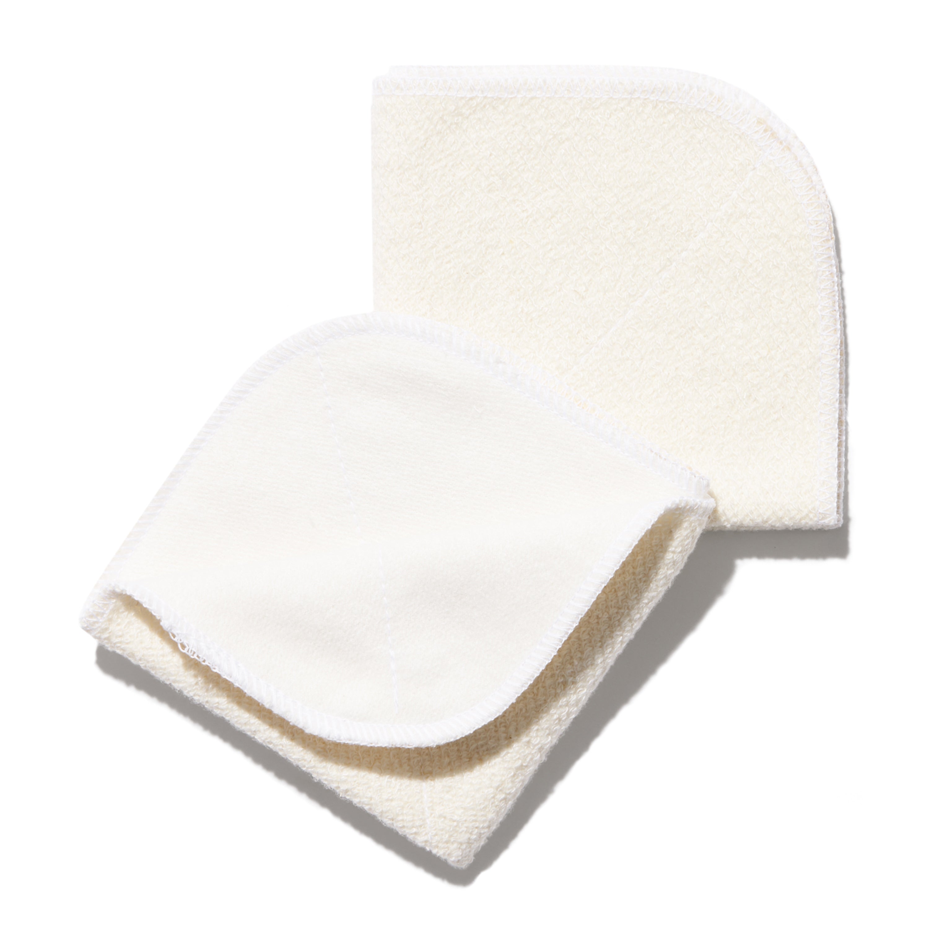 The Caress Reusable Cloths from NOT!CE Hair Co are two cream-colored pads made of handmade organic bamboo cloth with rounded corners and stitching, ideal for gentle cleansing. They are neatly stacked on a white background.