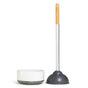 The Eco Plunger with Replaceable Head by Grove Co. is an eco-friendly toilet plunger featuring a wooden handle and a black rubber suction cup. It stands upright next to a white cylindrical holder with a black base, crafted from sustainable materials for durability and longevity.