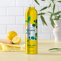 A 24oz Grove Co. Hydrating Hand Soap bottle with lemon and eucalyptus fragrance sits on a table, accompanied by a half lemon, whole lemon, yellow cloth, and plant against a white tiled wall. Text reads Go Beyond Plastic.